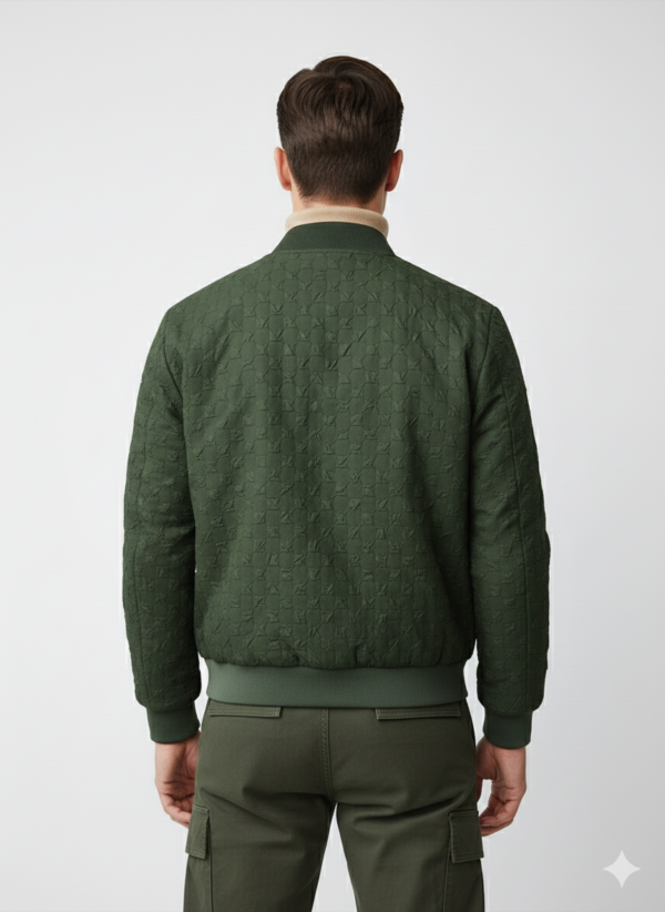 A man standing on a waterfront pier wearing a dark olive green textured bomber jacket over a beige ribbed turtleneck sweater and matching cargo pants.